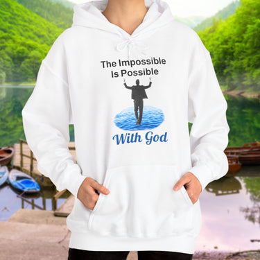 Gildan unisex hoodie with “Impossible Man” design featuring a man walking on water and uplifting message, Christian apparel made from soft cotton-poly blend, perfect for cold weather and spiritual encouragement, woman in white hoodie